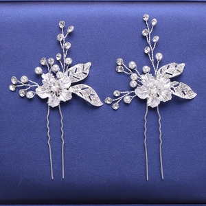 Dettaglio di due forcine per capelli da sposa in argento con cristalli e perle su blu