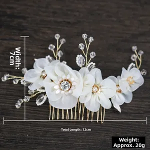 Detail view of handmade bridal hair comb with white fabric flowers and golden metal base