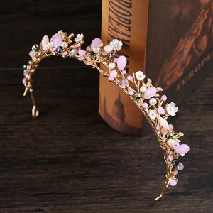 Détail d'un diadème floral en cristal rose avec fil d'or et perles sur des livres