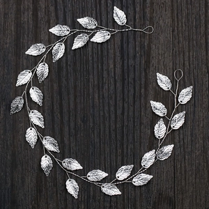 Macro detail of silver leaf bridal hair vine with lifelike vein textures on wooden background