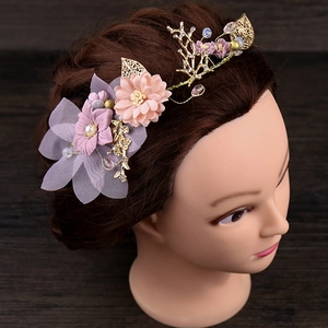 Détails de fleurs en tissu rose et feuilles dorées sur le serre-tête de mariée