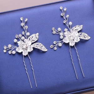 Dettaglio di due forcine da sposa argentate con perle e strass scintillanti su sfondo