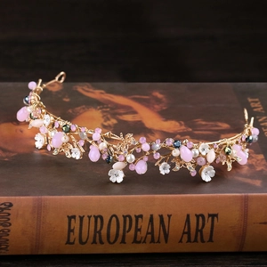 Détail d'un diadème doré de mariée avec cristaux roses posé sur un livre d'art ancien