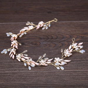 Detailed macro view of golden leaf bridal headband with pink enamel and white pearls