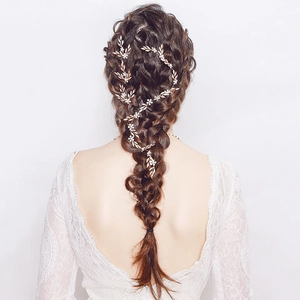 Detailed back view of a bride with golden leaf and pearl hair vine in a braid