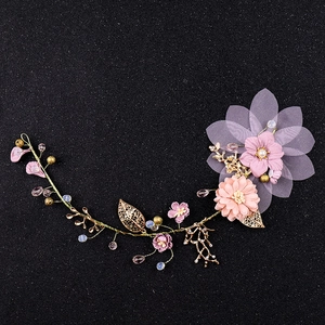 Détail d'une vigne de cheveux de mariée avec fleurs rose violet et feuilles dorées