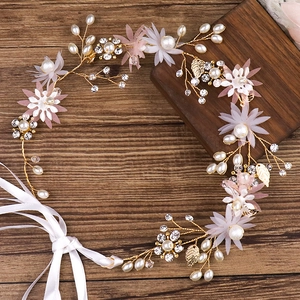 Détail de fleurs en tissu rose et perles blanches sur un bandeau de mariée doré