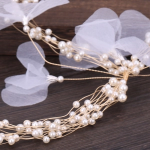 Detail of bridal hairband with white pearls and delicate organza flower petals