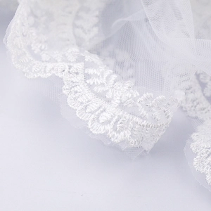 Detailed macro view of white wedding veil featuring intricate floral lace embroidery