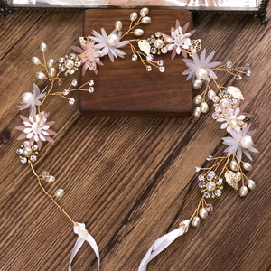 Détails d'une vigne de cheveux de mariée avec fleurs en tissu rose et perles sur bois sombre