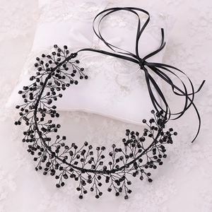 Close-up of handmade black beaded headband with red pearls and leaf design on white lace