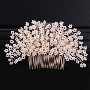 Macro shot of handmade bridal hair comb with white pearls and gold wire flowers
