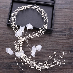 Close-up of handmade white pearl hair vine with mesh flowers on a wooden background