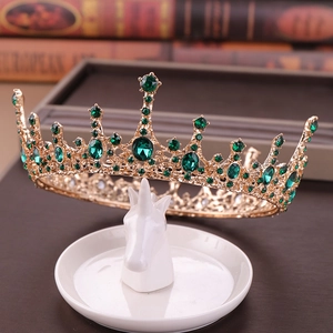 Royal vintage gold bridal crown featuring emerald green rhinestones on unicorn stand