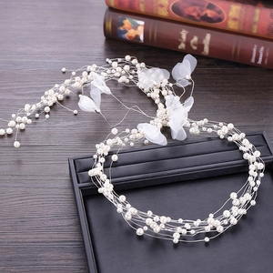 Close-up of bridal headpiece with white organza flowers and pearls on vintage book