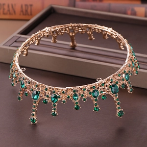 Detailed close-up of vintage golden crown with emerald green rhinestones and baroque tassels