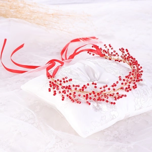 Handmade bridal headband with red beads and golden leaf vine on white lace cushion