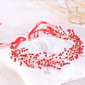 Close-up of handmade red crystal beads and gold wire leaf bridal headband with ribbon
