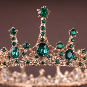 Macro detail of vintage gold crown featuring intricate hollow patterns and emerald green gems