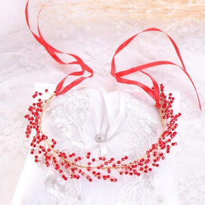 Detail of handmade bridal headband with red beads and golden wire on lace background