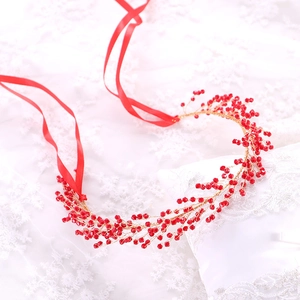 Detailed macro view of handmade red beaded bridal headband with gold wire and ribbon