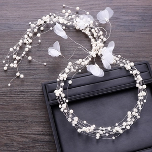 Close-up of bridal headpiece with white pearls and delicate fabric flowers on silver wire