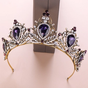 Close-up of a vintage gold baroque crown featuring large purple crystals and small rhinestones