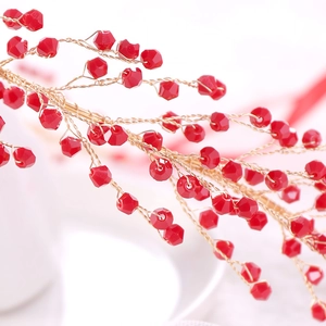 Macro shot of handcrafted gold wire hairband with vibrant red faceted beads for weddings