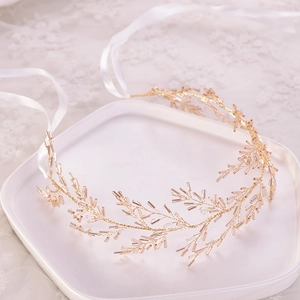 Détail d'accessoire de cheveux doré fait main avec perles et rubans en satin blanc
