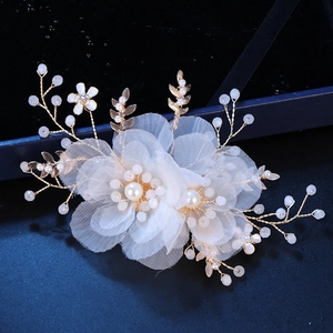 Detail of handmade bridal hair comb with white fabric flowers and golden pearl accents