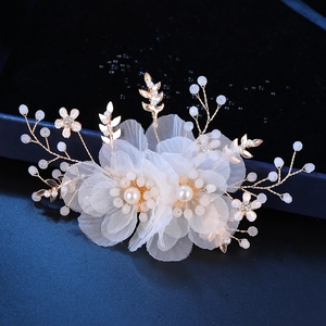 Macro shot of white mesh floral hair clip with intricate gold wire and pearl beadwork