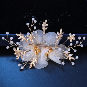 Detail of the golden wire structure and white petal beads on a bridal hair clip