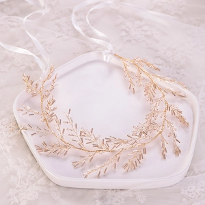 Vue détaillée d'une coiffe de mariée artisanale en fil doré ornée de perles champagne