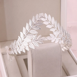 Macro detail of silver vintage leaf crown with intricate texture on a grey velvet stand
