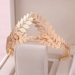 Close-up of golden laurel leaf crown with detailed vein textures on a jewelry stand