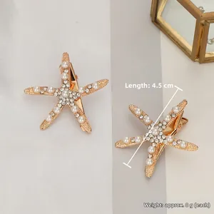 Vue détaillée d'une pince à cheveux étoile de mer dorée avec perles et strass brillants