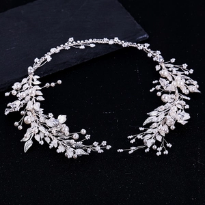 Macro shot of silver bridal hair vine with pearls and metal leaves on black background