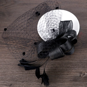 Detailed close-up of a vintage black fascinator with mesh veil, bow, and feathers