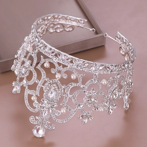 Detailaufnahme einer silbernen Krone mit Kristall-Strass und Perlen auf einem grauen Tablett