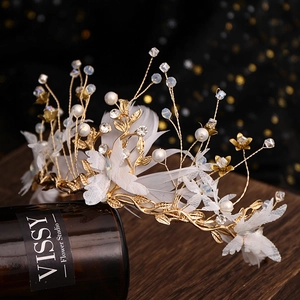 Detailed shot of handmade bridal crown with white feathers, pearls and gold wire
