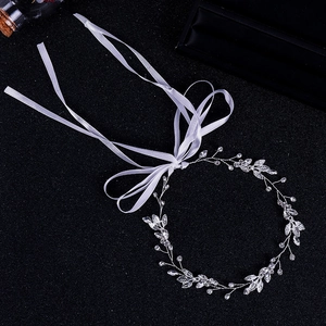 Détail du bandeau de mariée avec feuilles argentées et strass brillants et rubans blancs