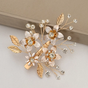 Détail d'une pince à cheveux fleurie dorée avec cristaux, perles et métal brossé