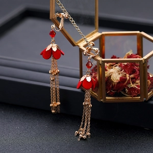 Dettaglio degli orecchini con fiori rossi e nappe su una scatola di gioielli vintage