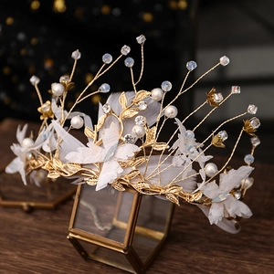 Close-up of bridal crown featuring delicate white feathers, lace butterflies and pearls