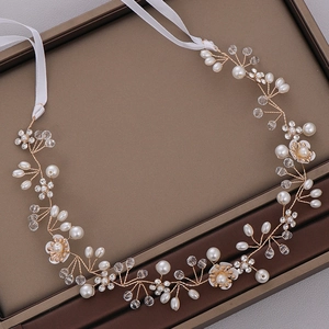 Close-up of handmade bridal headband with white pearls, crystals, and gold vine wire