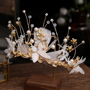 Detail of bridal gold crown with white feathers, pearls and crystal floral lace accents