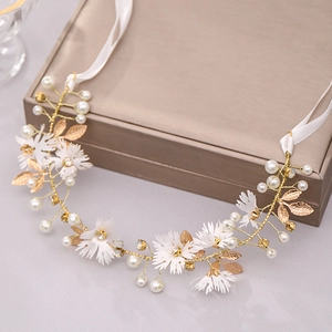 Close-up of handmade bridal headband with gold leaves, white flowers and pearls