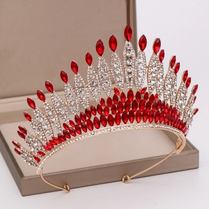 Detailed macro view of a luxury gold bridal crown with red and clear crystals in a jewelry box