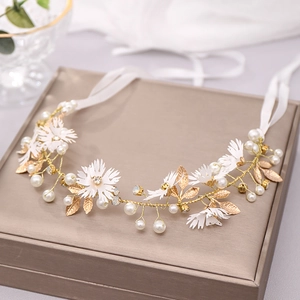 Detail of bridal floral headband with pearls, fabric flowers and gold leaves on satin ribbon