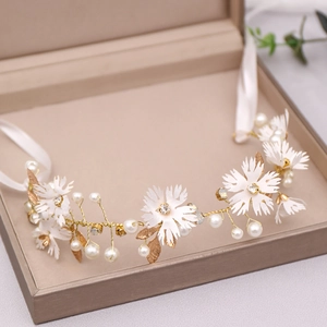 Detail of white fabric flowers with faux pearls and rhinestones on a gold bridal headband